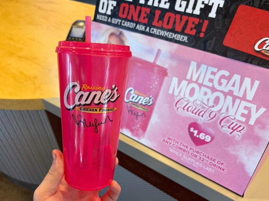 a hand holding a hot pink plastic cup with cane's logo on it