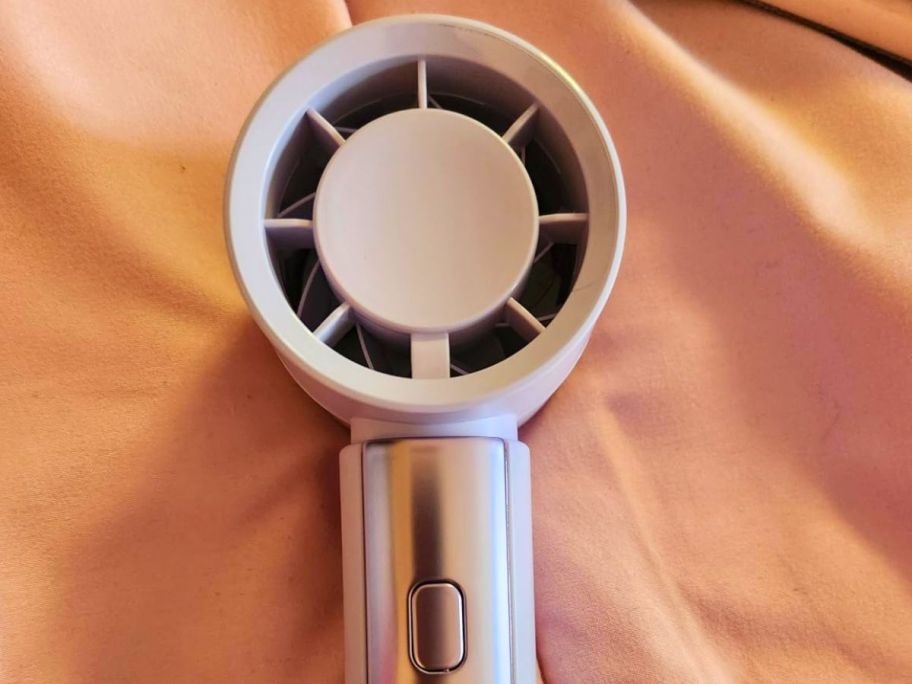 pink mini fan on top of the bed