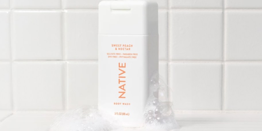 native body wash bottle with bubbles in shower