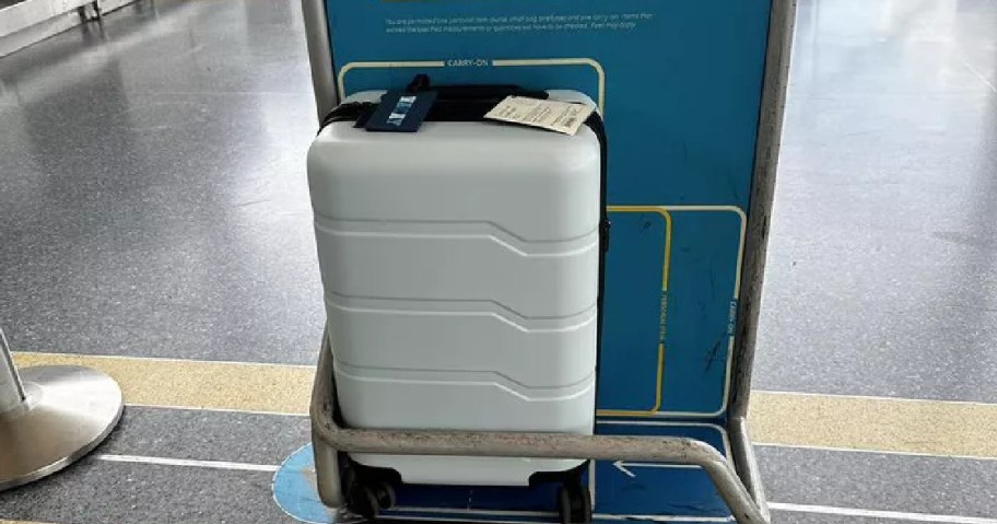 A white hardshell carry-on suitcase.