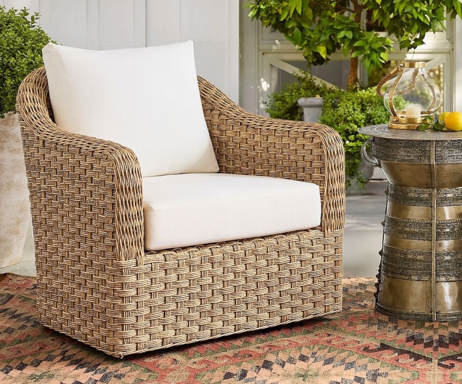wicker chair with white cushions on outdoor rug