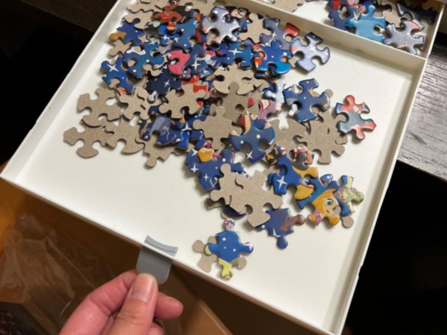 hand holding a puzzle table drawer full of puzzle pieces