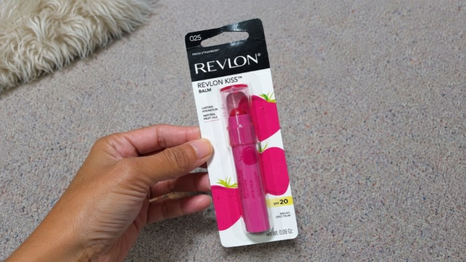 a hand holding a packaged tube of lip balm