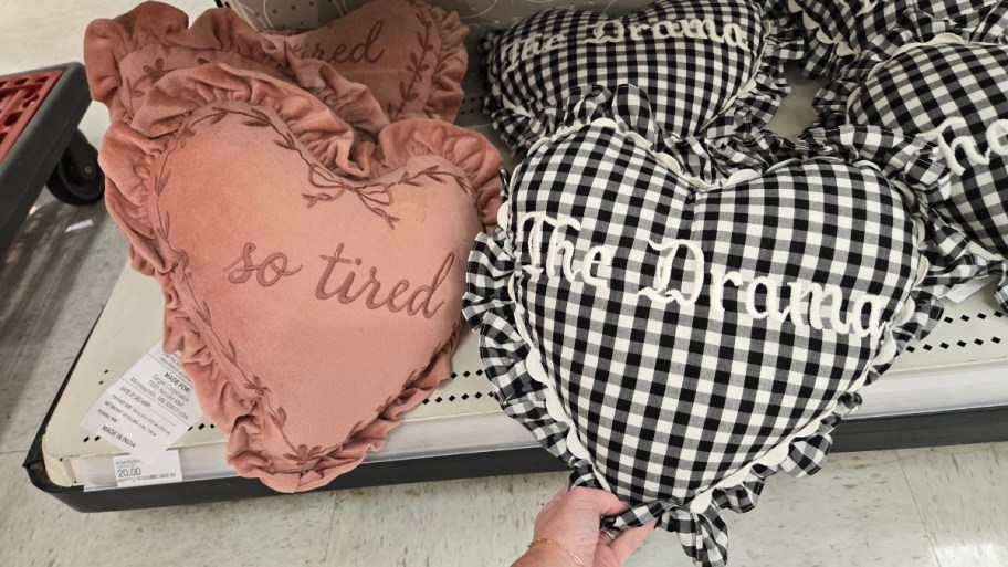 womans hand holding a heart shaped throw pillow