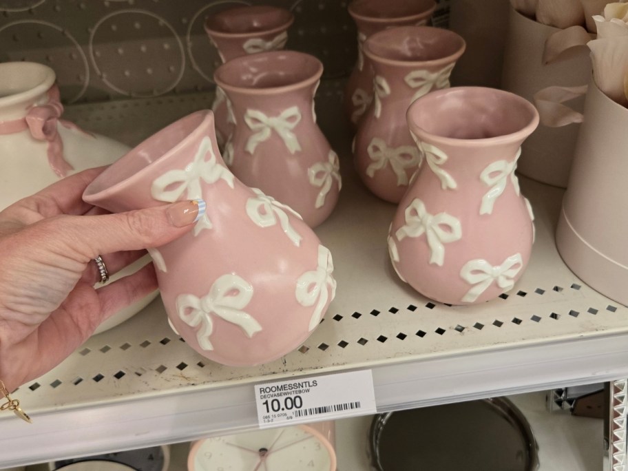 a hand reaching for a pink vase on a store shelf