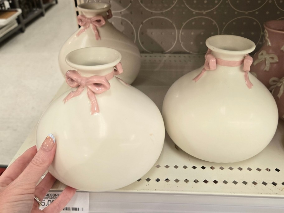 a hand reaching for a white vase on a store shelf