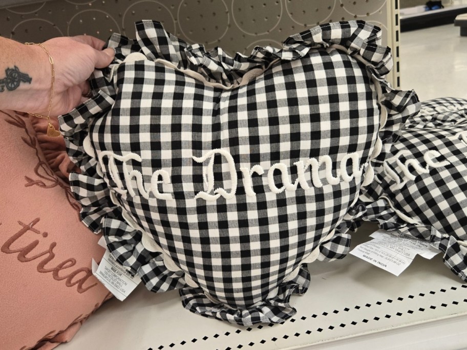 womans hand holding a heart shaped throw pillow