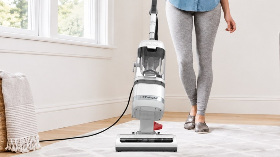 a woman using a white shark lift away vacuum