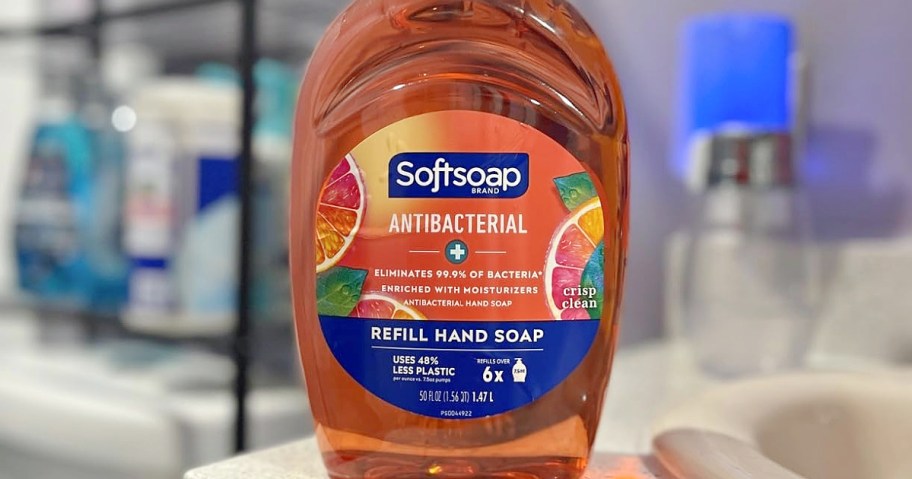 A large refill bottle of orange Softsoap Antibacterial hand soap sitting on a bathroom counter.