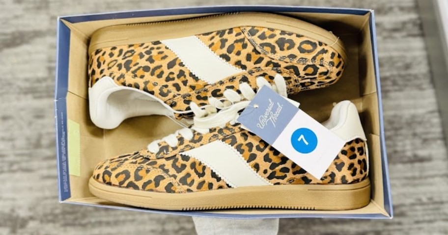 hand holding a shoe box with women's leopard print sneakers in them