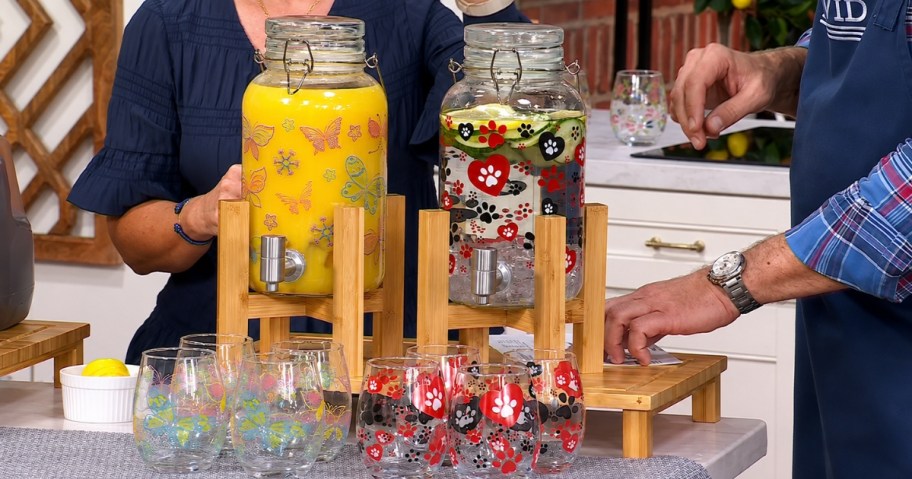 two glass drink dispensers with matching cups