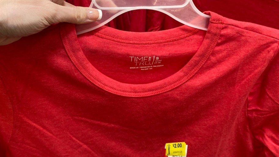 womans hand holding a clearance tee