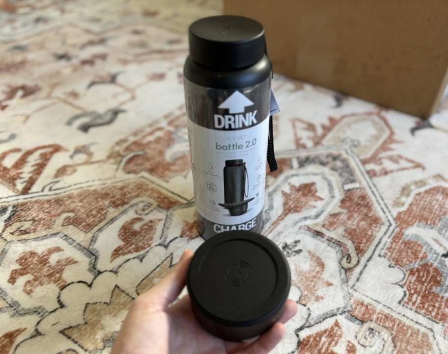 a hand holding the wireless charging part of the power bank water bottle