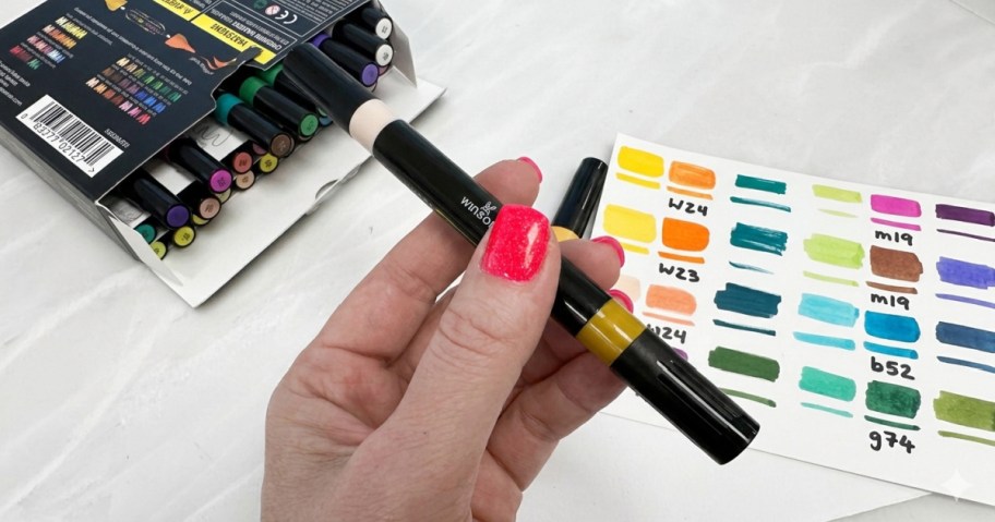 hand holding a paint marker with a box and swatch in the background