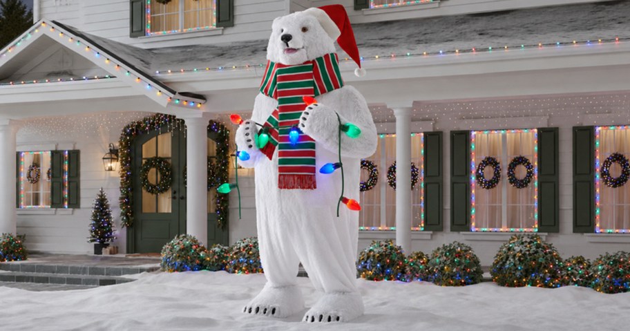 Giant lighted Christmas polar bear displayed in front of a decorated home