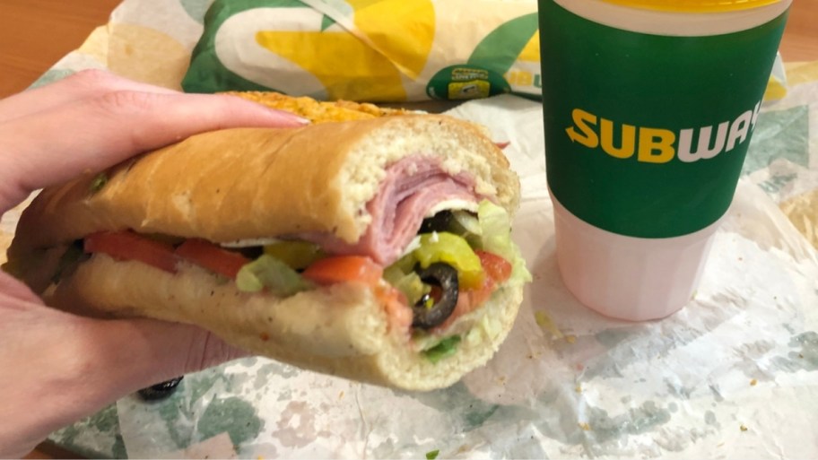 a woman's hand holding a subway sandwich