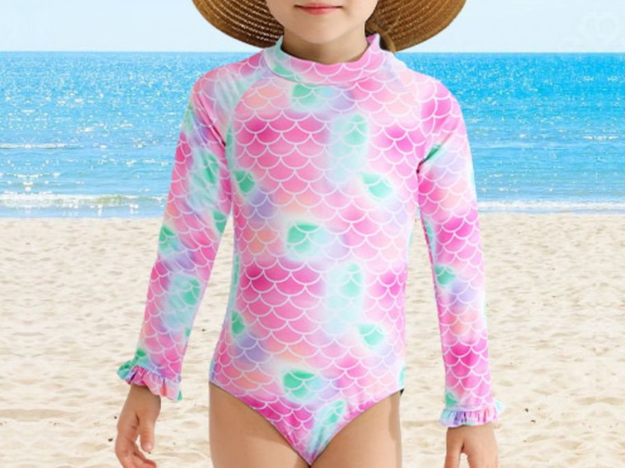 Little girl wearing a mermaid scale print rash guard swimsuit