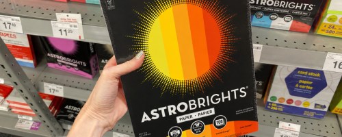Hand holding up Astro brights construction paper inside staples store