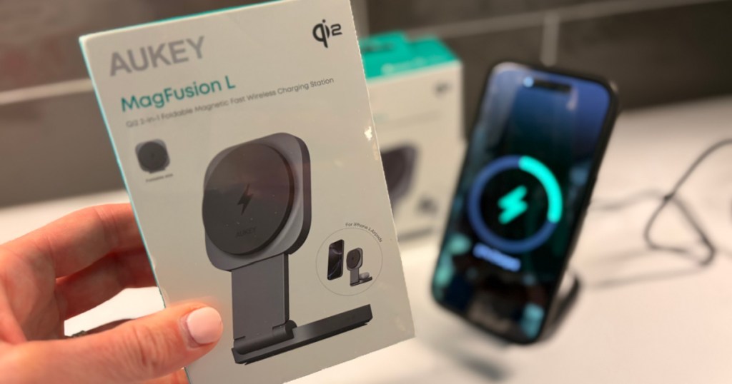 Woman holding box of Aukey magfusion, wireless chargers, while iPhone, charging in background
