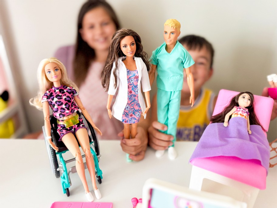 girl and boy holding up barbie and ken dolls