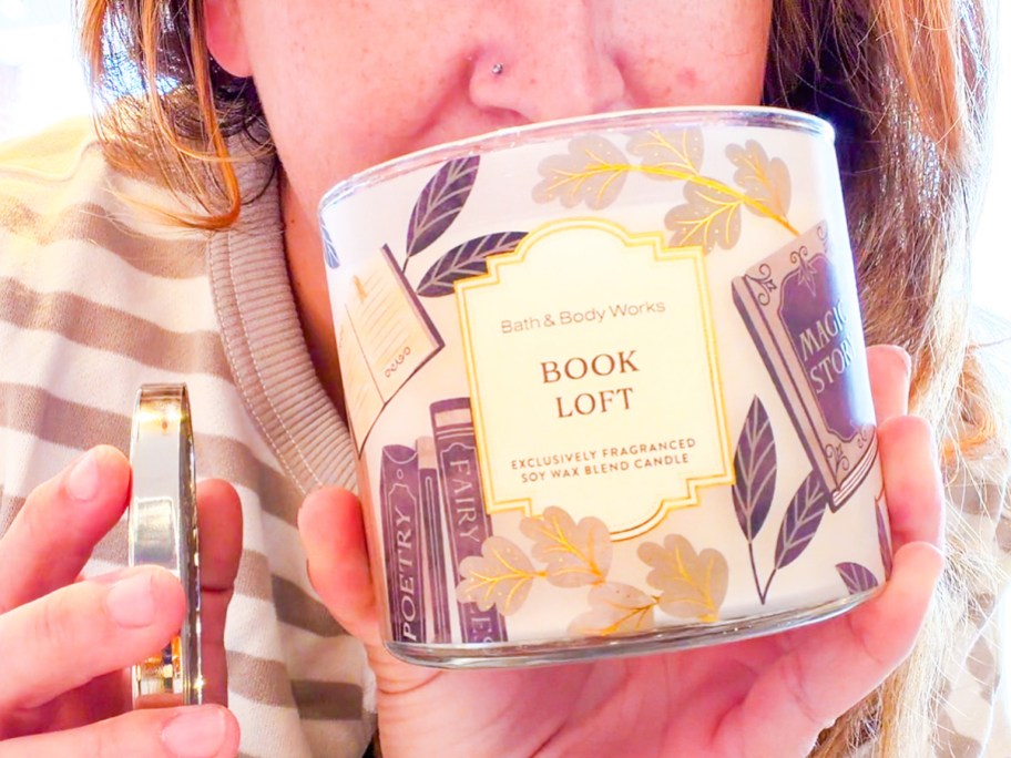 woman smelling a book loft candle
