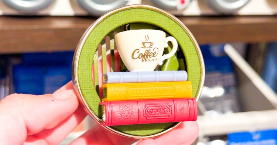 hand holding a coffee mug and books fragrance holder