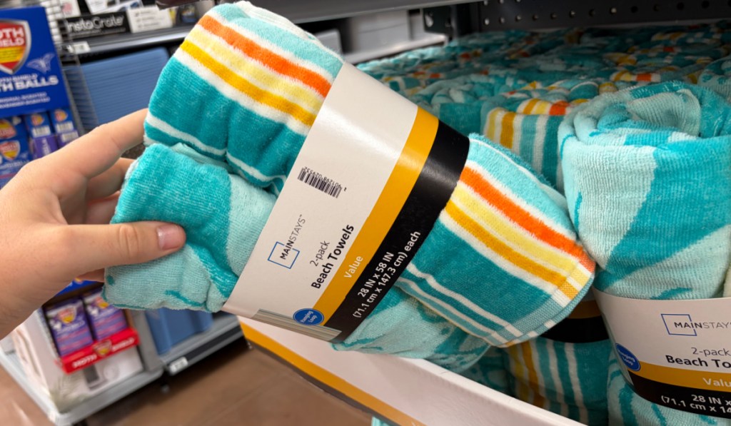 Hand grabbing two pack of beach towels inside Walmart store