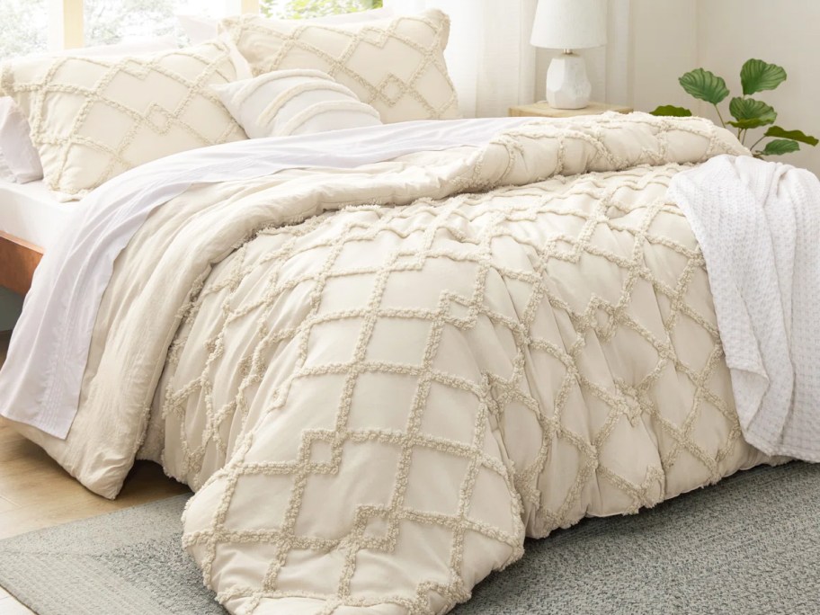 cream comforter and shams set on a bed with white sheets