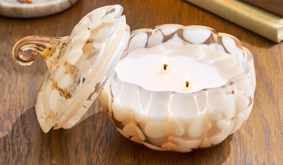 glass pumpkin jar candle lit on a table