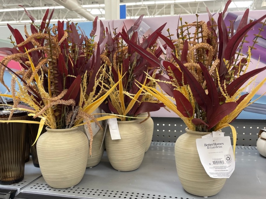 fall colored artificial plants in vases on a store shelf
