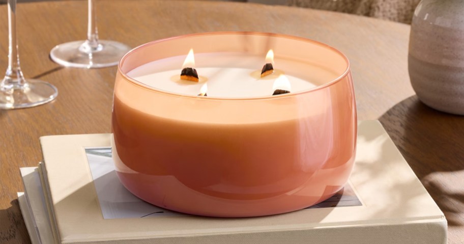 orange 4 wooden wick candle on a stack of books