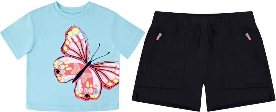A light blue t-shirt featuring a large pink and red butterfly graphic paired with black athletic shorts featuring zippered pockets and a drawstring waist.