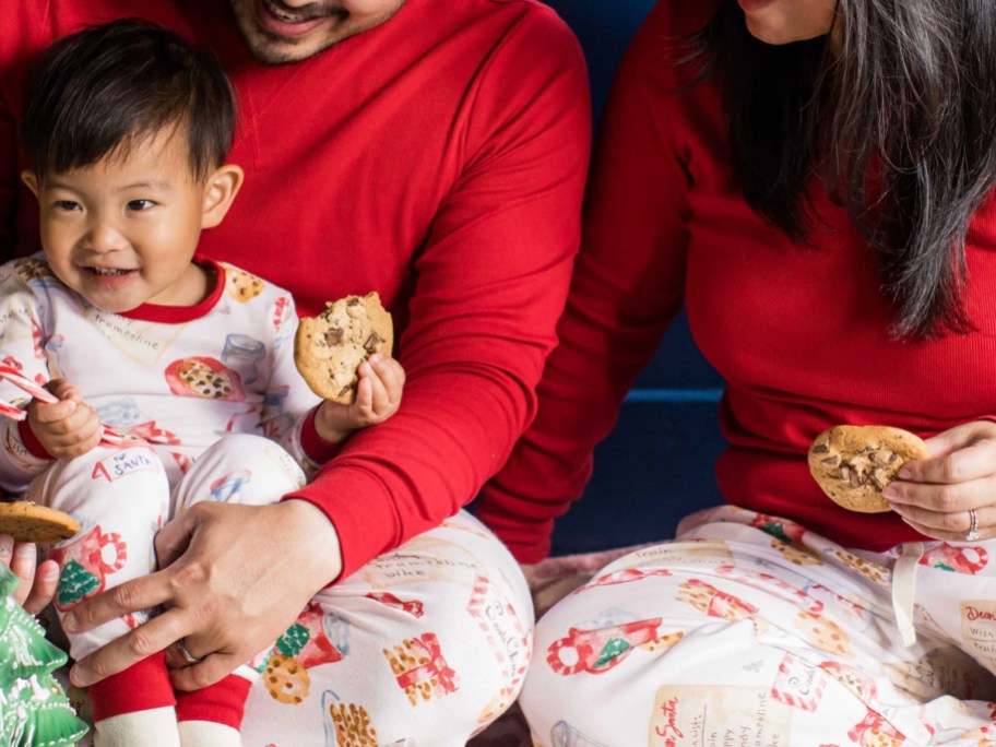 Family wearing burts bees Christmas pajamas, and eating cookies