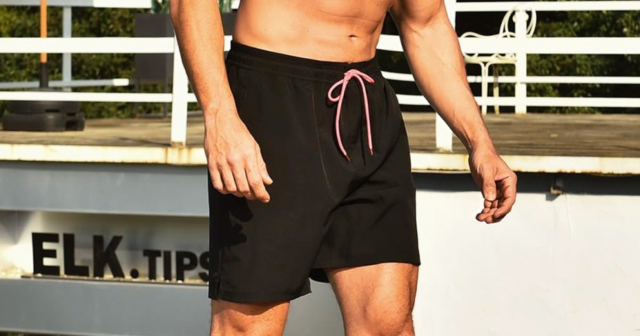 man wearing pair of black swim trunks with pink ties