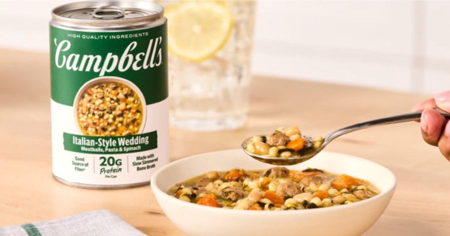 A can of Campbell's Italian-Style Wedding Protein Soup next to a bowl of soup and a spoon.