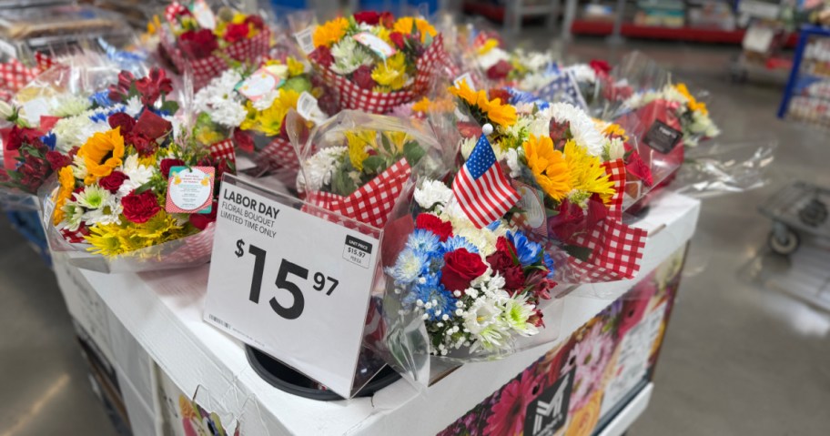 A display of Labor Day floral bouquets priced at $15.97, featuring red, white, and yellow flowers decorated with small American flags.