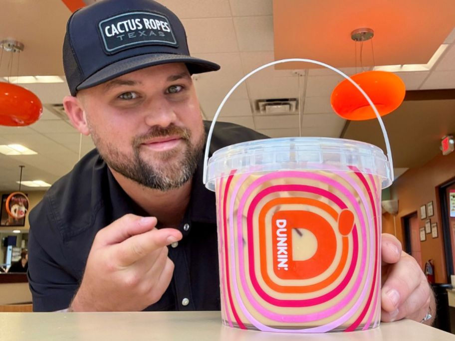 Man pointing at a bucket of Dunkin coffee