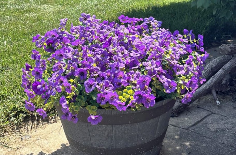 purple artificial flowers in a barrel planter