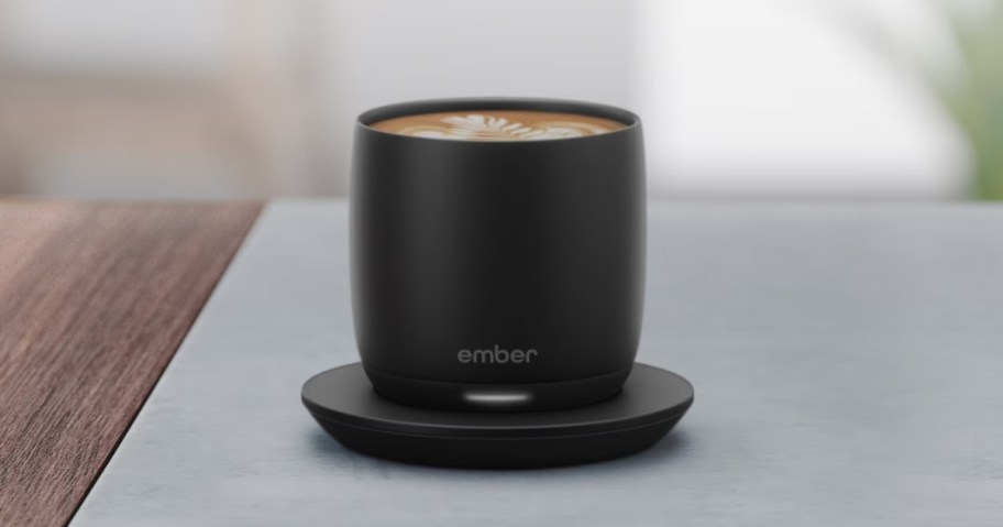 black ember smart cup sitting on charger coaster in kitchen with latte in cup