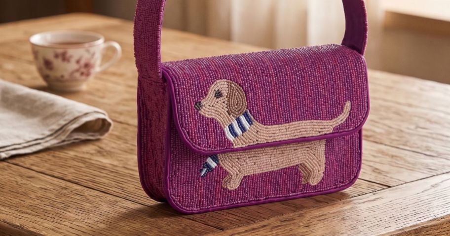 maroon Free Assembly Women's Beaded Flap Shoulder Bag with Dachshund sitting on table