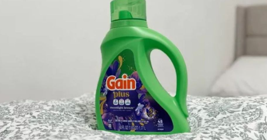 Gain Moonlight Breeze Plus Liquid Laundry Detergent 60oz bottle on bed