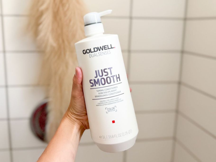 A hand holding a liter of Goldwell Conditioner