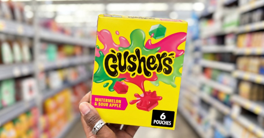 hand holding up a box of gushers in a store aisle