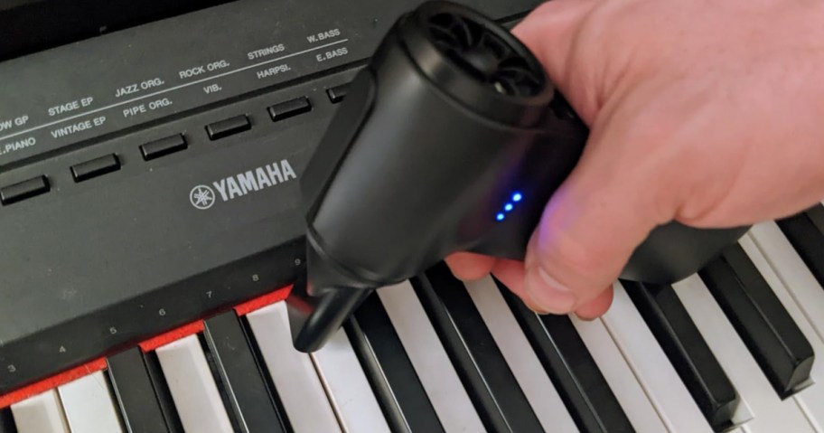 person using cordless air duster on a keyboard