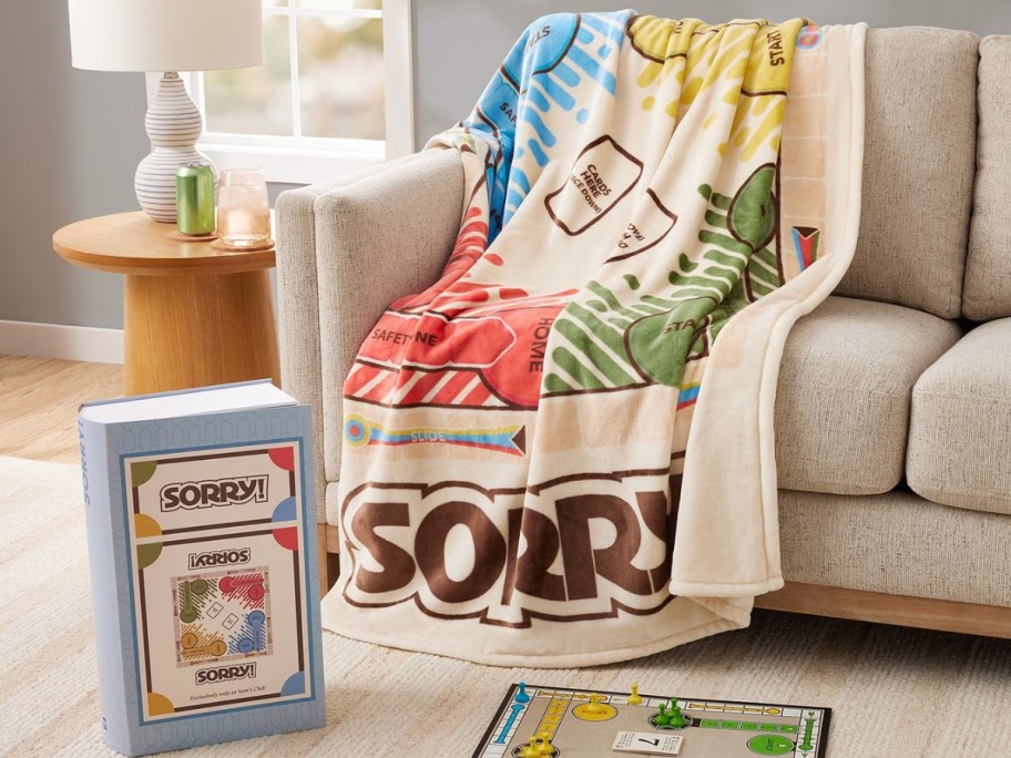 hasbro sorry board game blanket draped over couch with game box and board sitting on floor