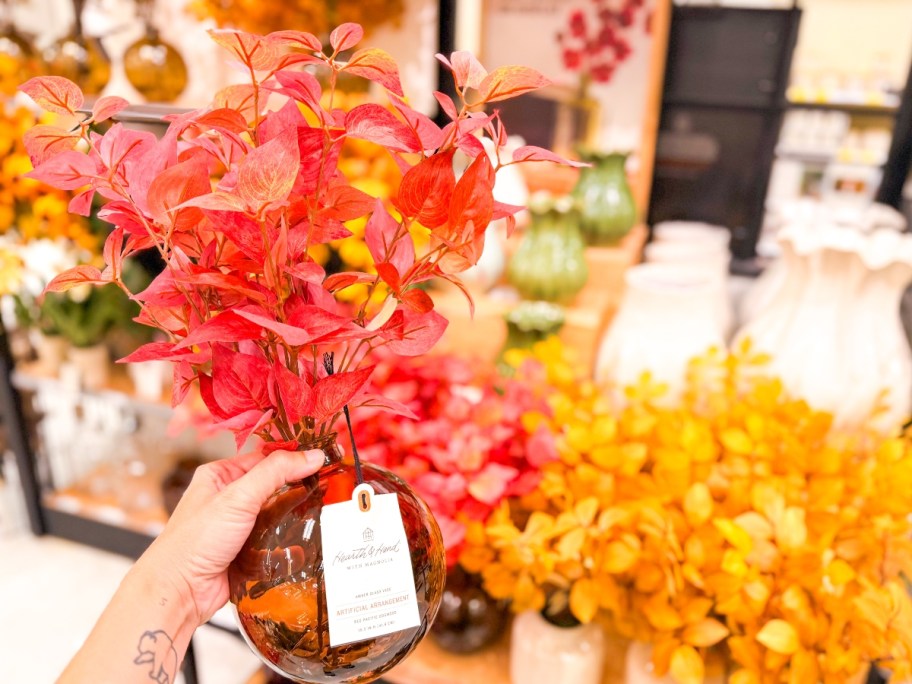 holding an amber vase with a red floral arrangement 