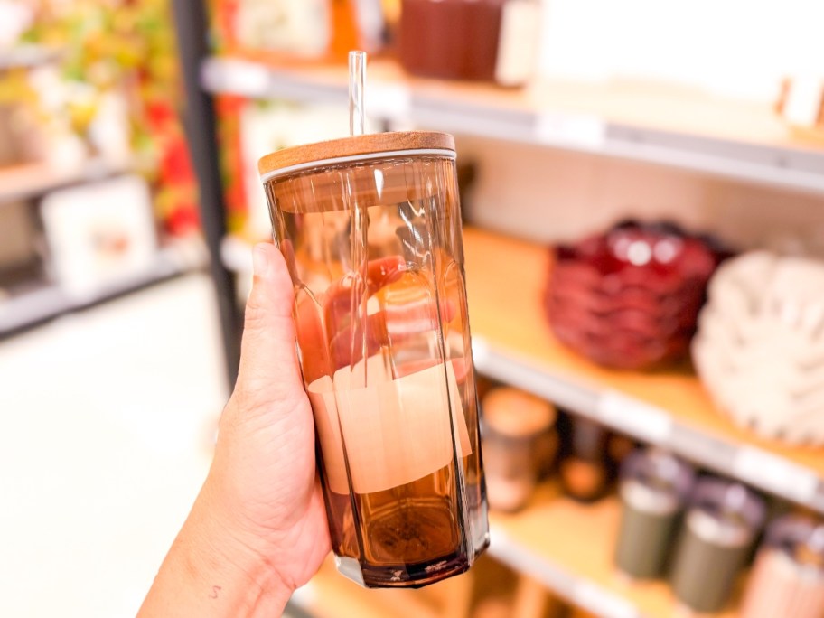holding a tan glass tumbler