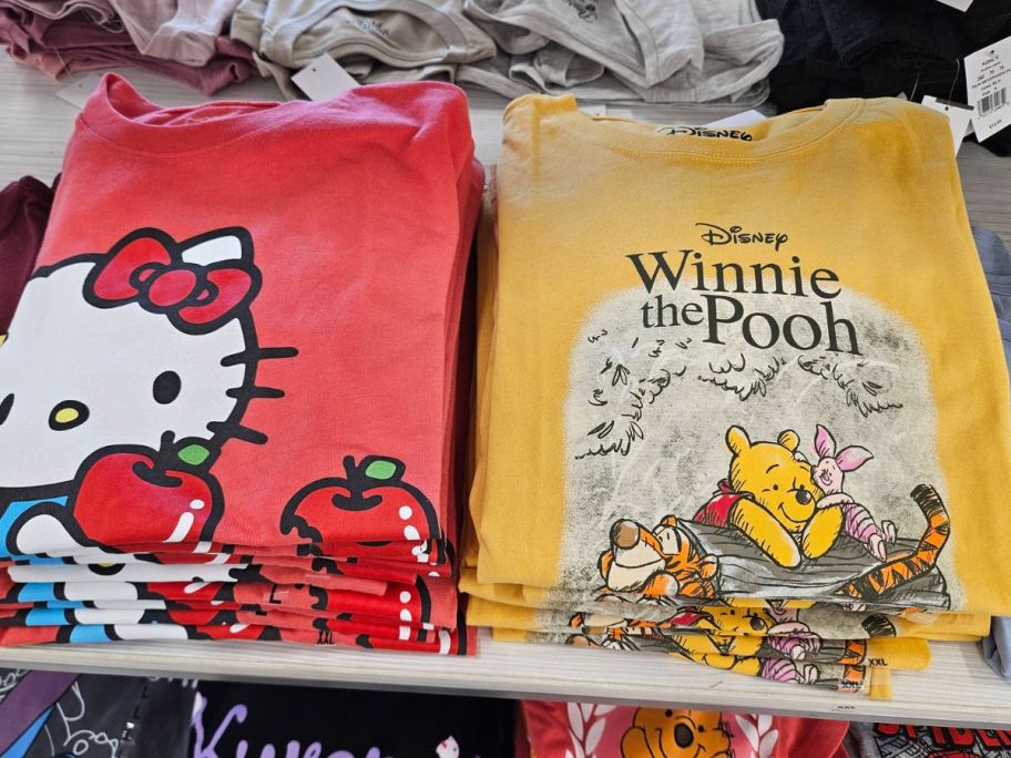 red Hello kitty and winnie the pooh graphic tees on top of a store table