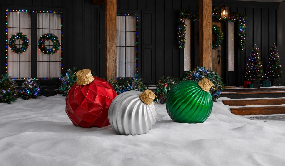 Red, silver, and green jumbo Christmas ornaments displayed in the snow