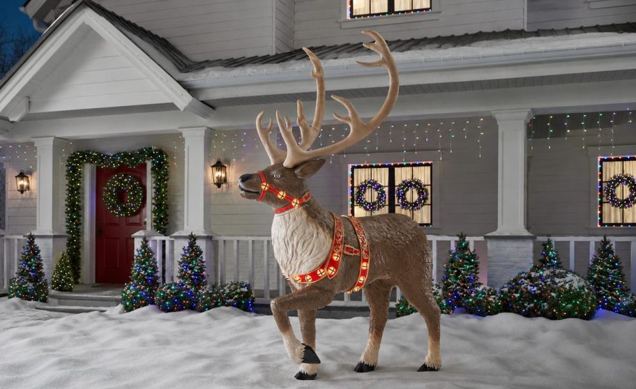 Giant lighted Christmas reindeer displayed in a snowy decorated yard